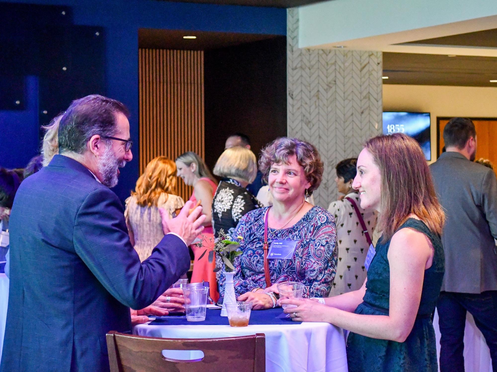 Group of faculty guests chat together around table