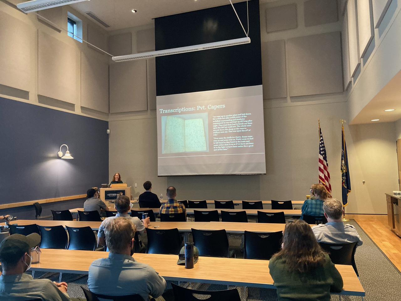 A classroom style room with a group of people looking at a presentation on the board.