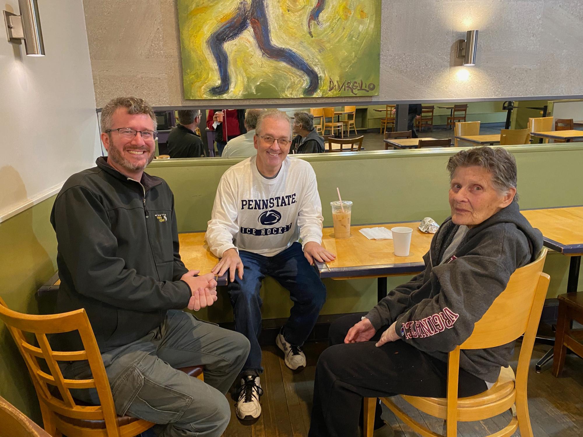 Three individuals sit around a table in a coffee shop.