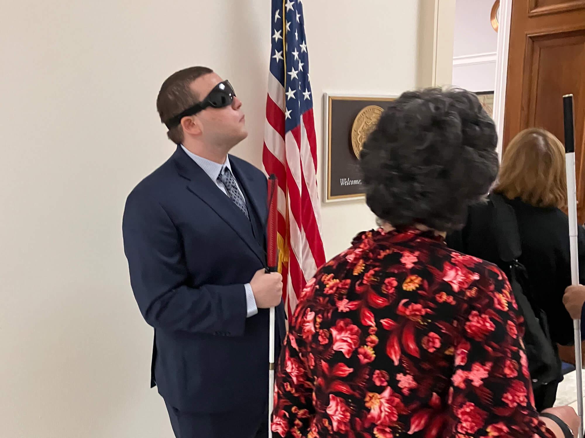 Tyler Hoppe standing in a suite while holding the American flag outside a Congressional office in Washington, DC.