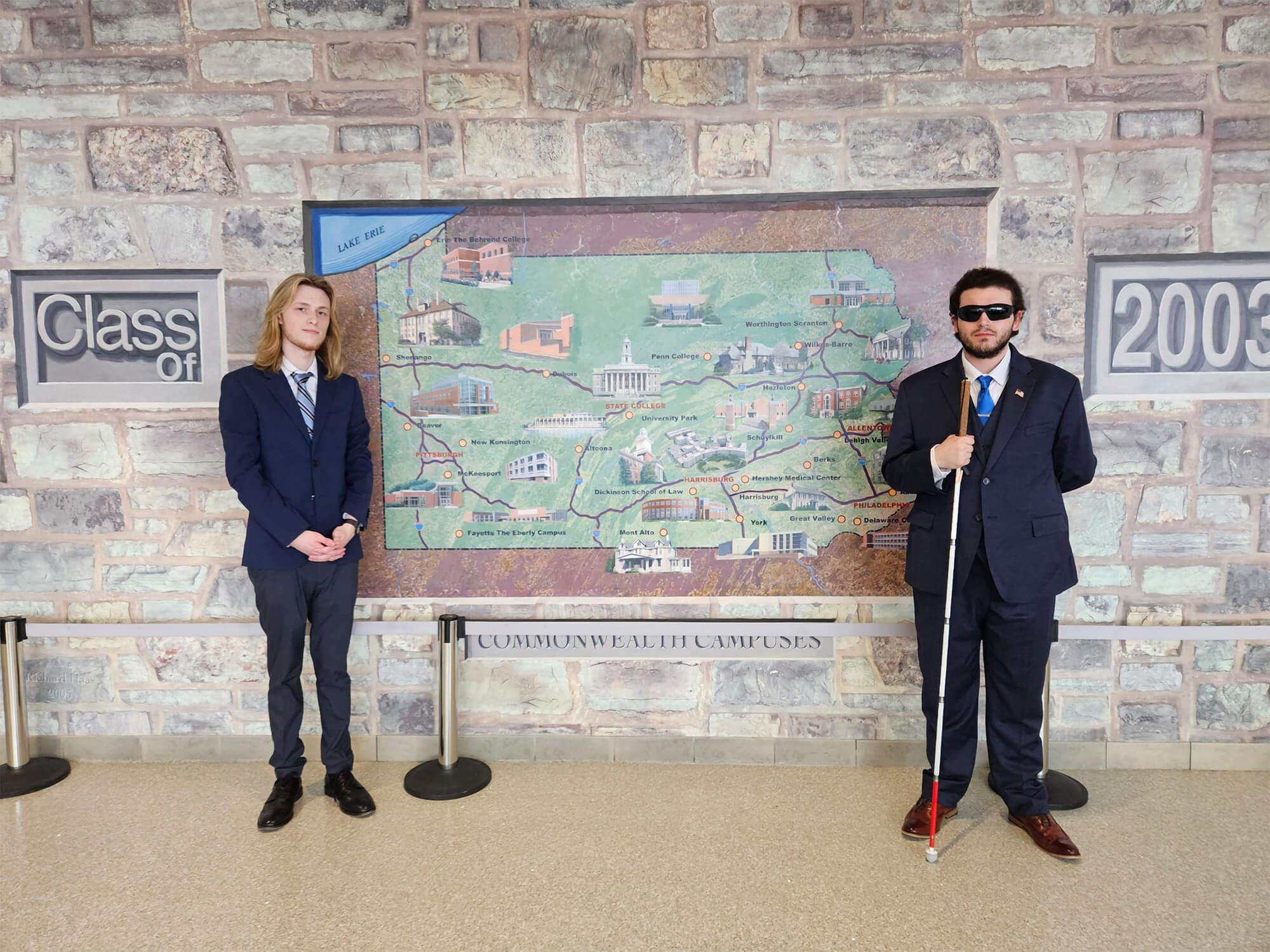 Tyler Hoppe (right) and Ethan Galley (left) stand in front of a map of Pennsylvania that displays all of the Penn State campuses inside the HUB-Robeson Center.