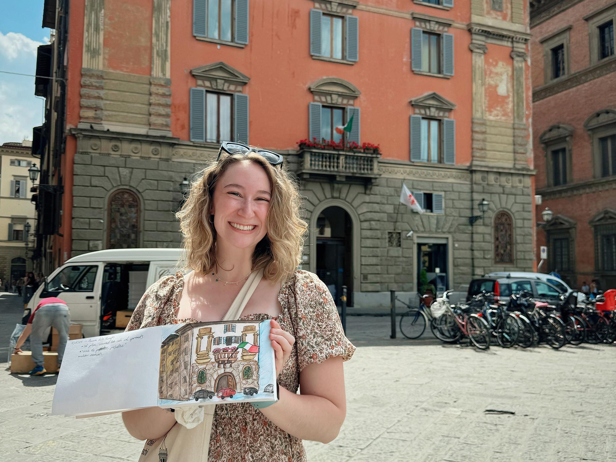 Katherine Marakovits holding a painting of the building behind her
