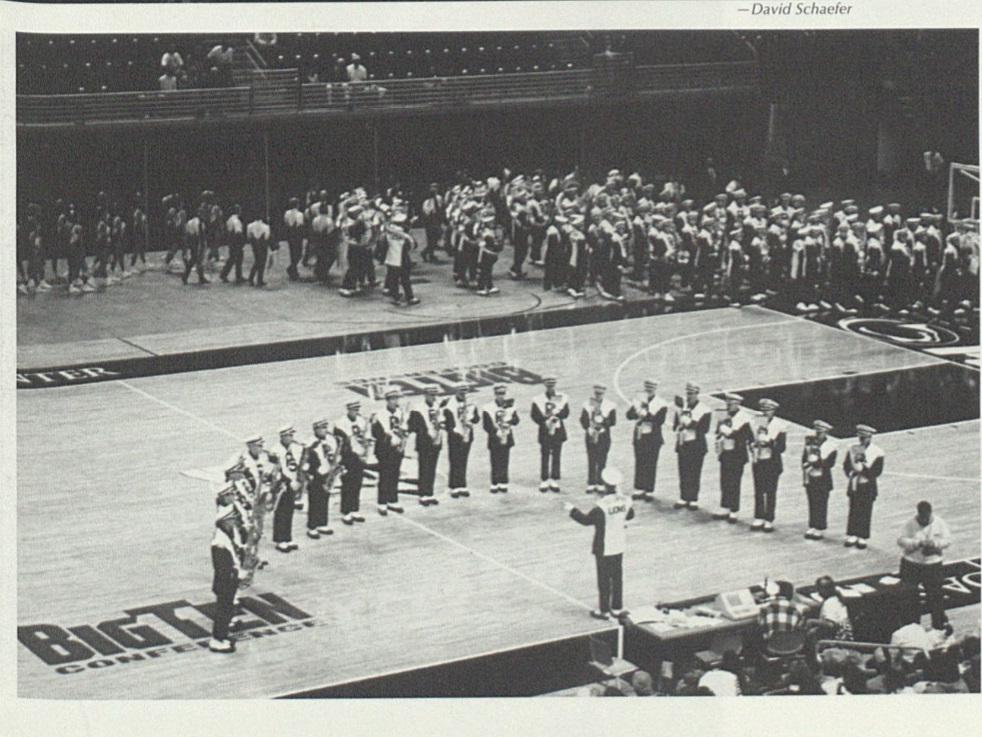 Members of a band stand in a semi circle on a basketball court