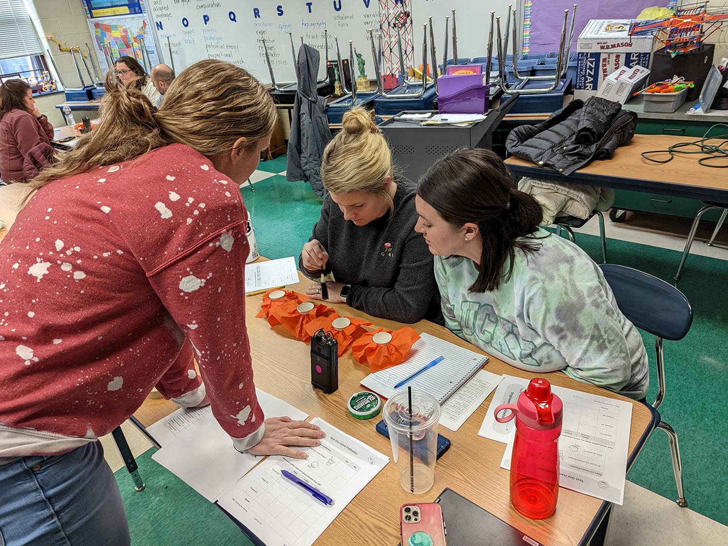 Three teachers work on a project together at a table.