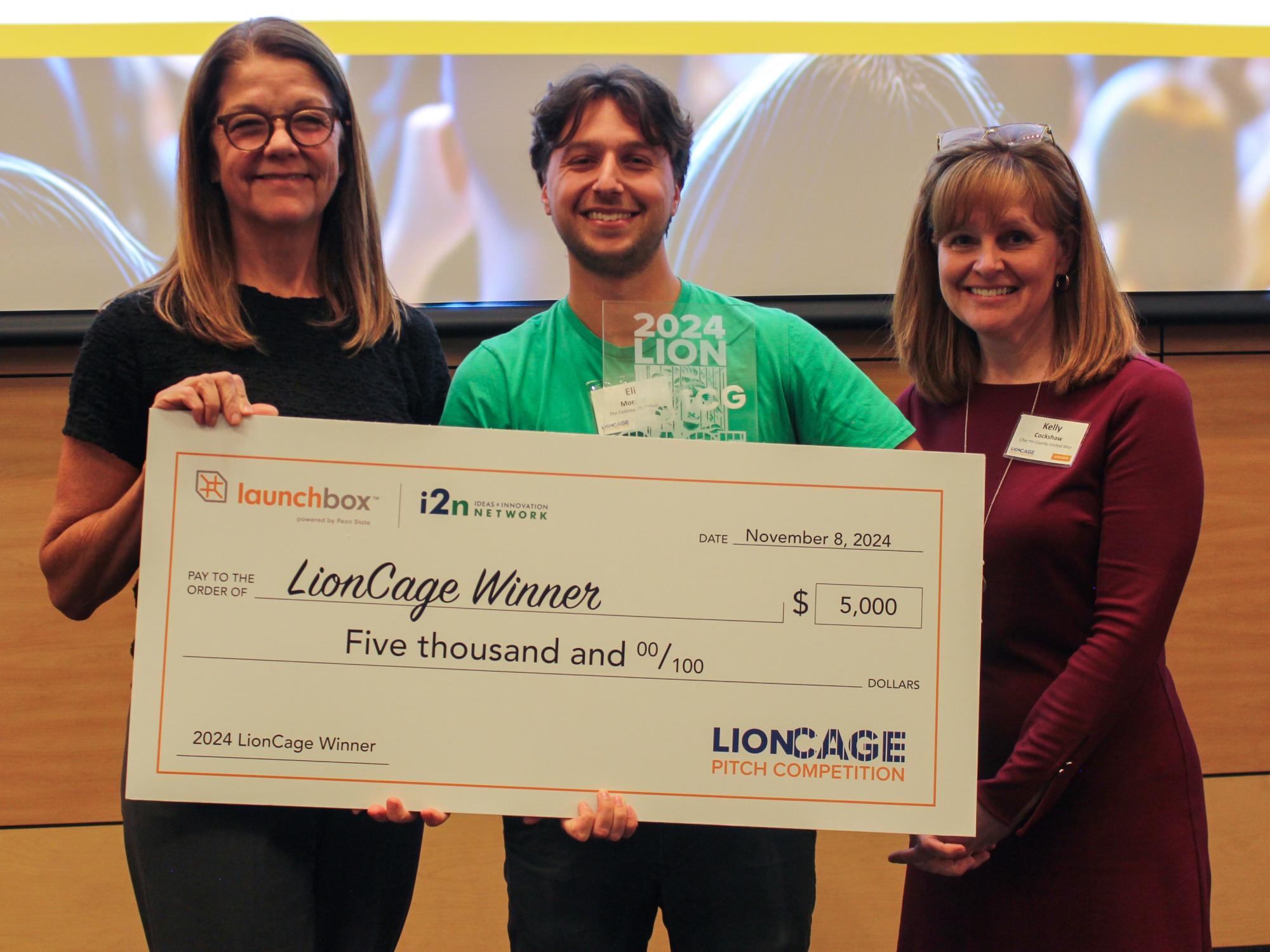 Eli Moraru, co-founder of the Community Grocer, poses with a giant check with prize money for his winning pitch.