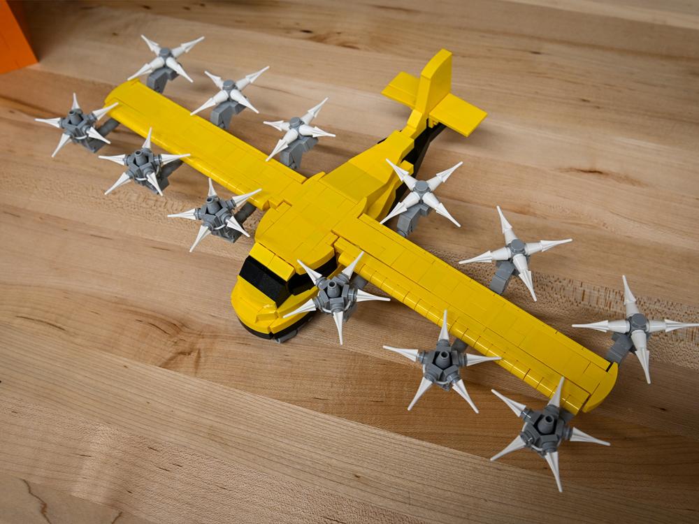  A yellow and black LEGO model of a plane is seen from above.
