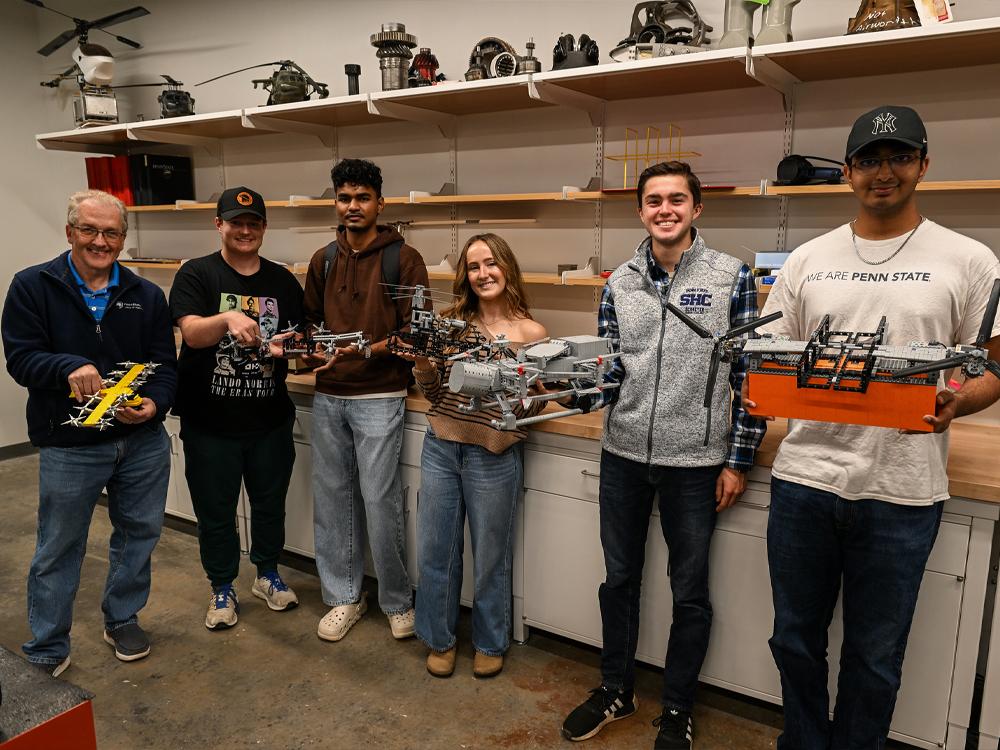 Six individuals holding LEGO models pose for a photo in the lab.    