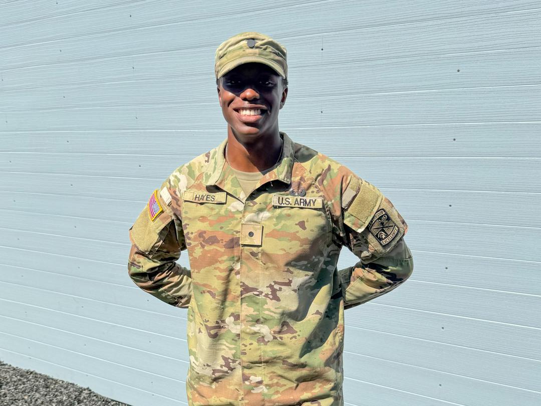 David Hayes stands in his Army uniform in front of a white wall.