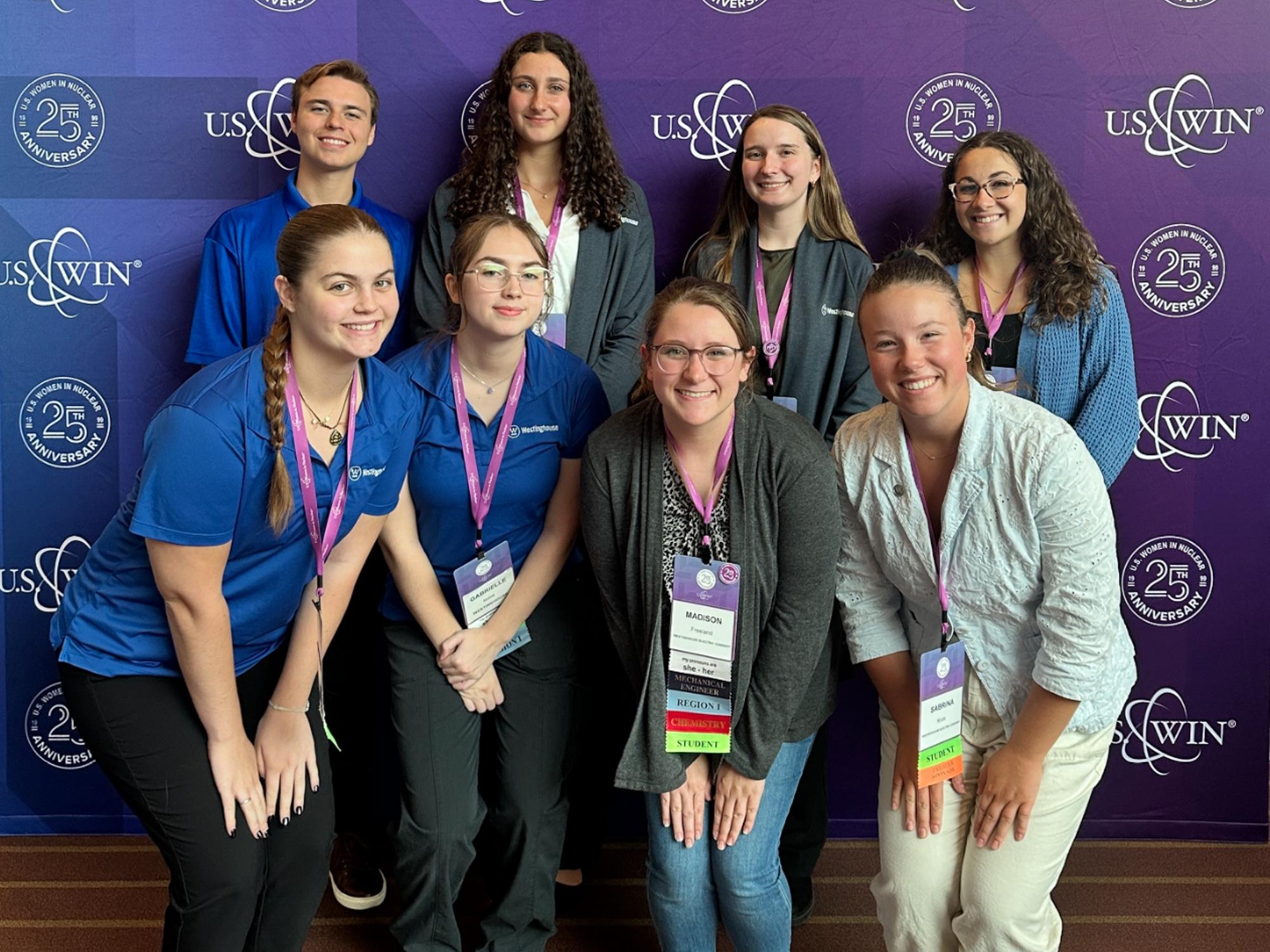 Two rows of four college students stand in front of a purple U.S. Women in Nuclear backdrop, including Sabrina Knox (bottom right).