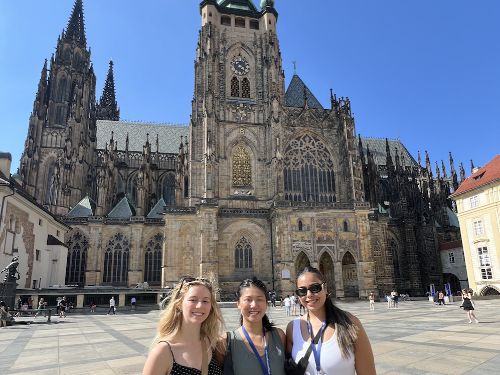 Jessica Krieger (left) stands with two other KPMG interns in a square in front of Prague Cathedral in Czechia.