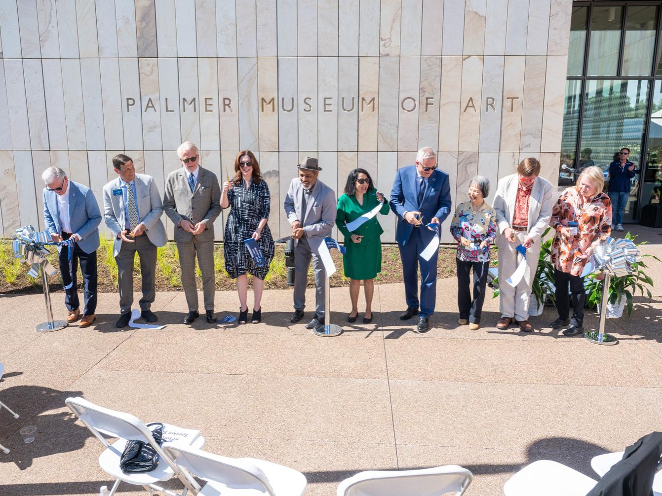 A group of people cut a ribbon in front of the new Palmer Museum of Art