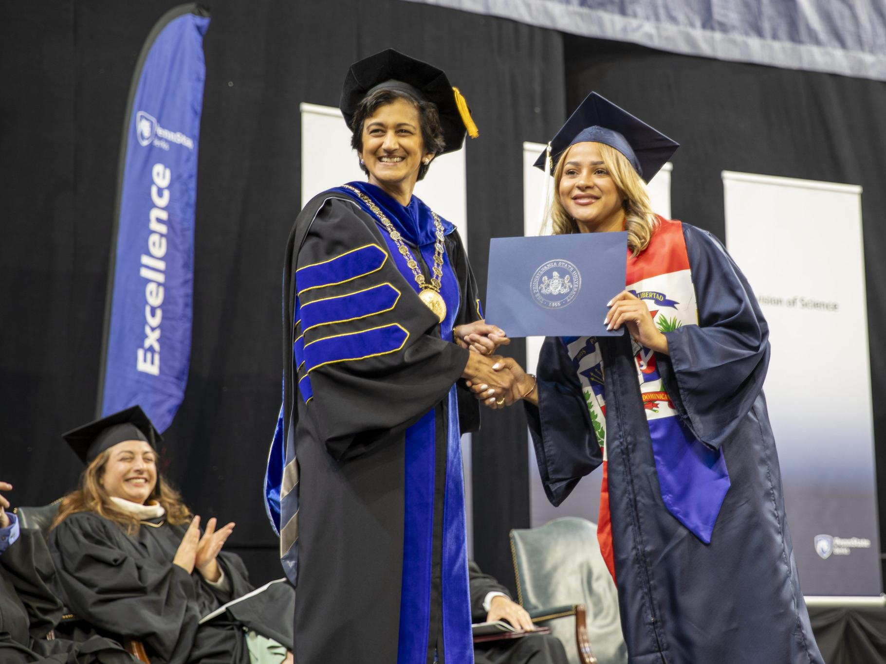 Chancellor Pyati poses with a graduate on stage