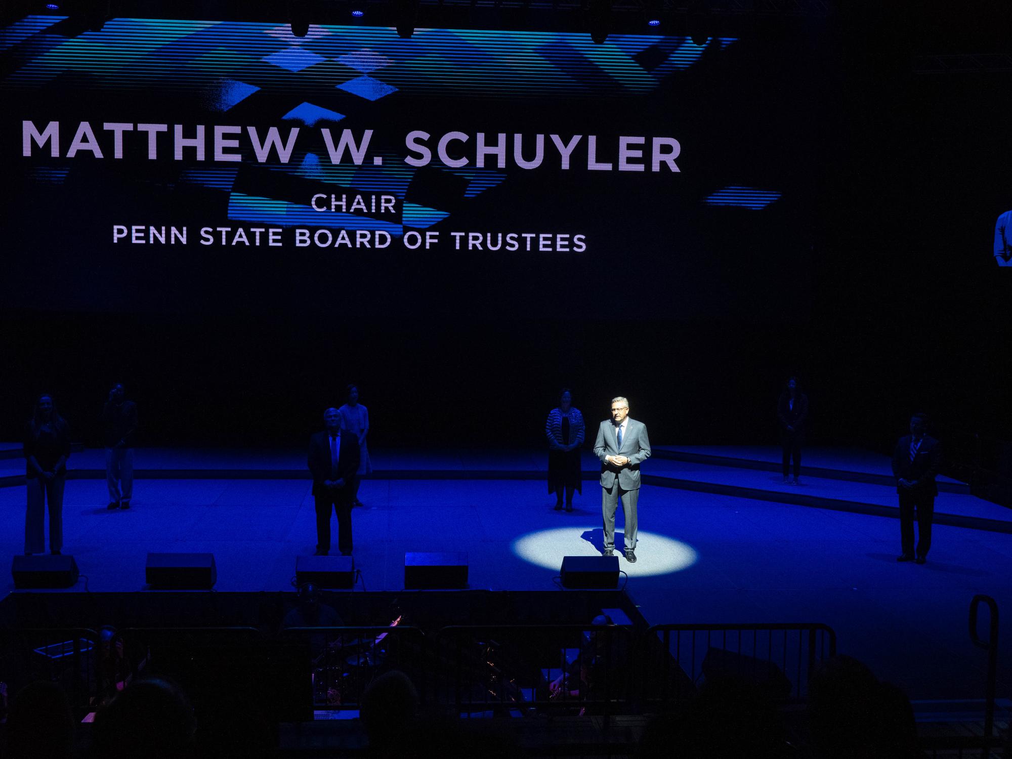 A spotlight shines on Matt Schuyler, who is standing on a stage