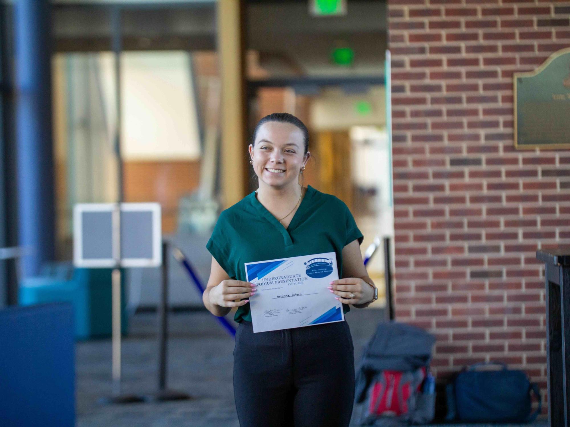 Brianna Sutara accepts the first-place prize for the undergraduate podium presentation at the Biology and Ecology Student Research Showcase on Nov. 1, 2024.