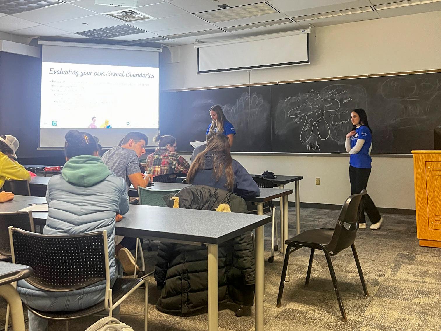 Sarah Stein standing in front of a classroom presenting a PowerPoint presentation.