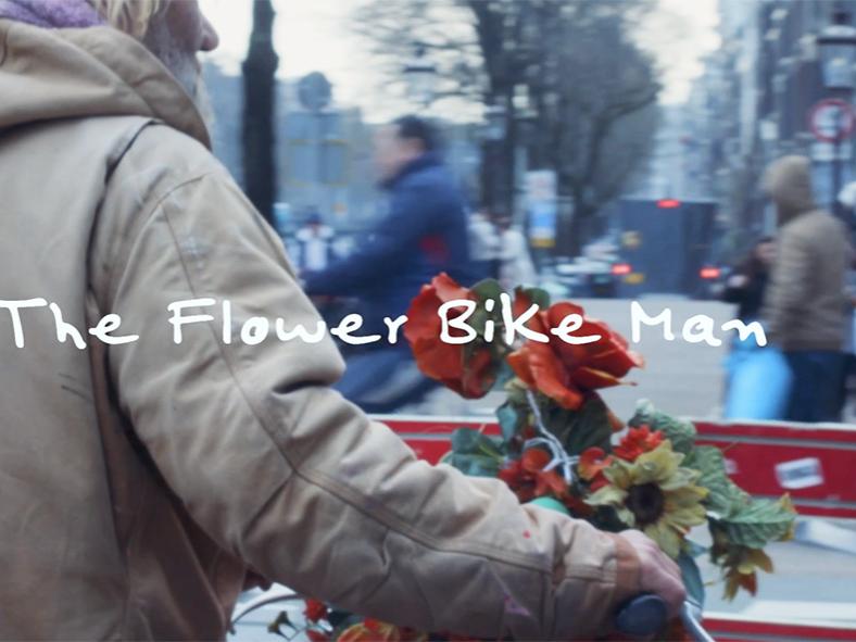 Man in heavy coat, pushing his bicycle with flowers on it