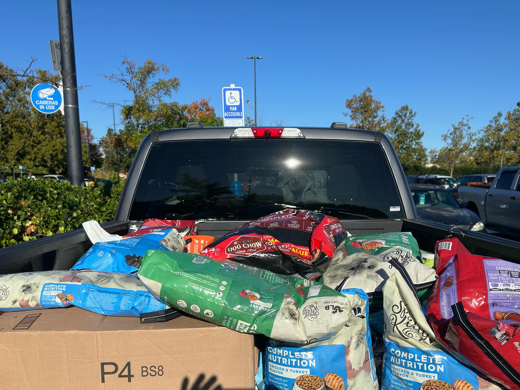 A truck bed full of bags of pet food and supplies.