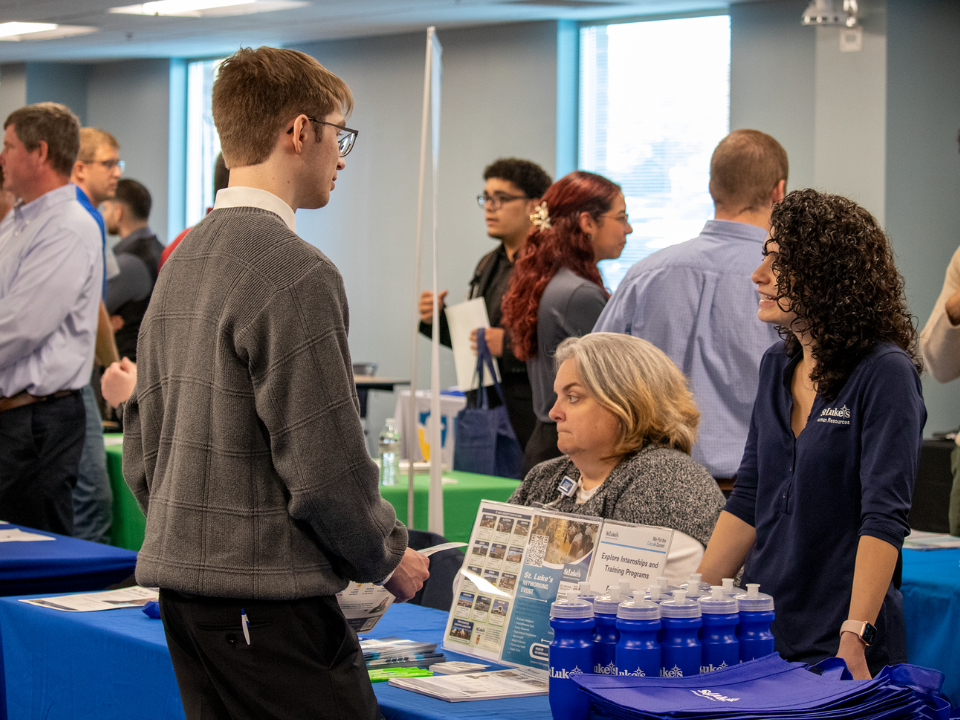 a male student speaks to a female employer at a job fair 
