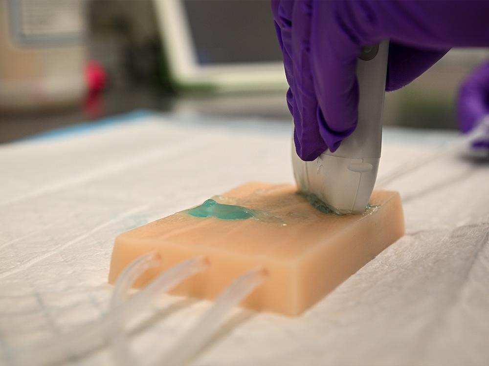 gloved hands manipulate an ultrasound transducer. 