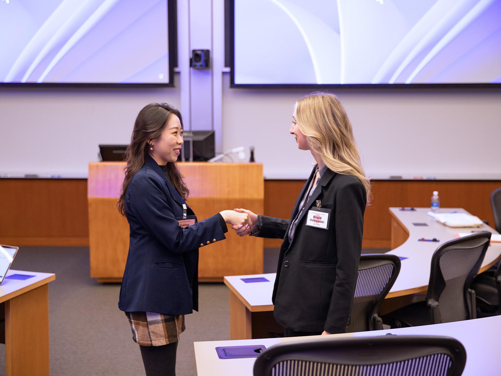 SIA students Yuting Zhang (left) and Brigid Ostrowski shake hands during a negotiation session.