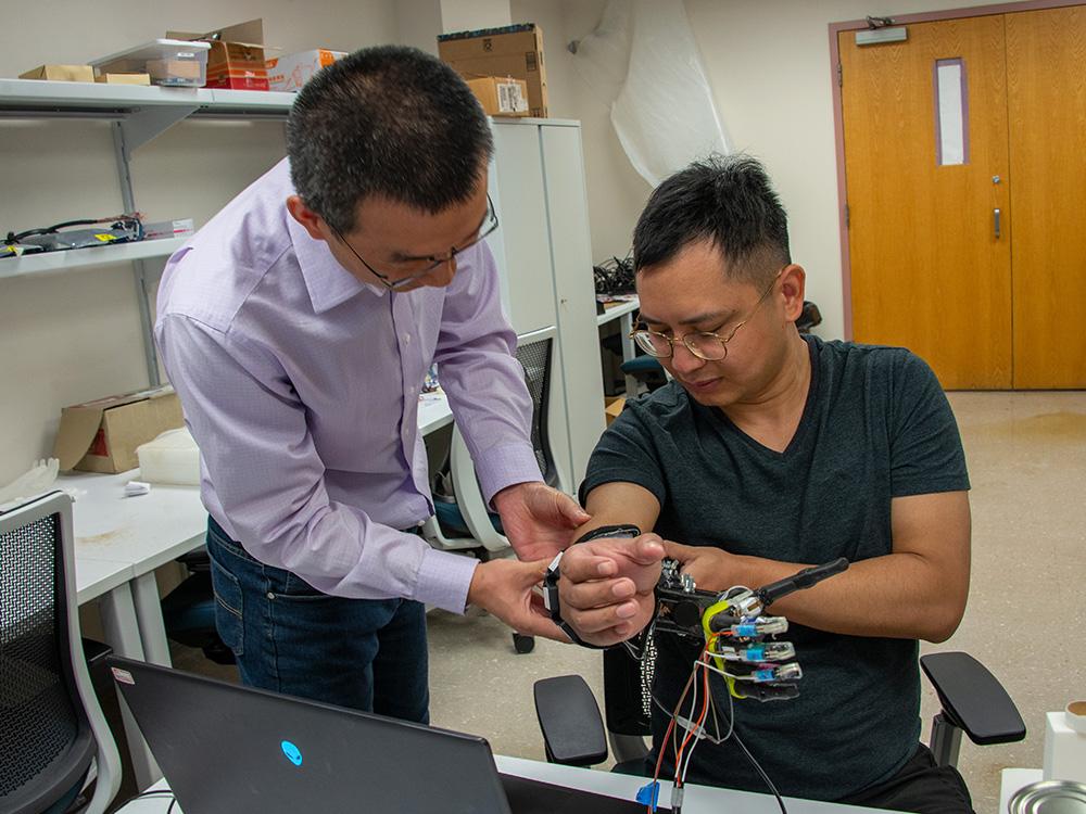 Two people adjust a prosthetic hand. 