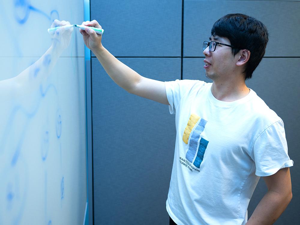 A student writes on a whiteboard