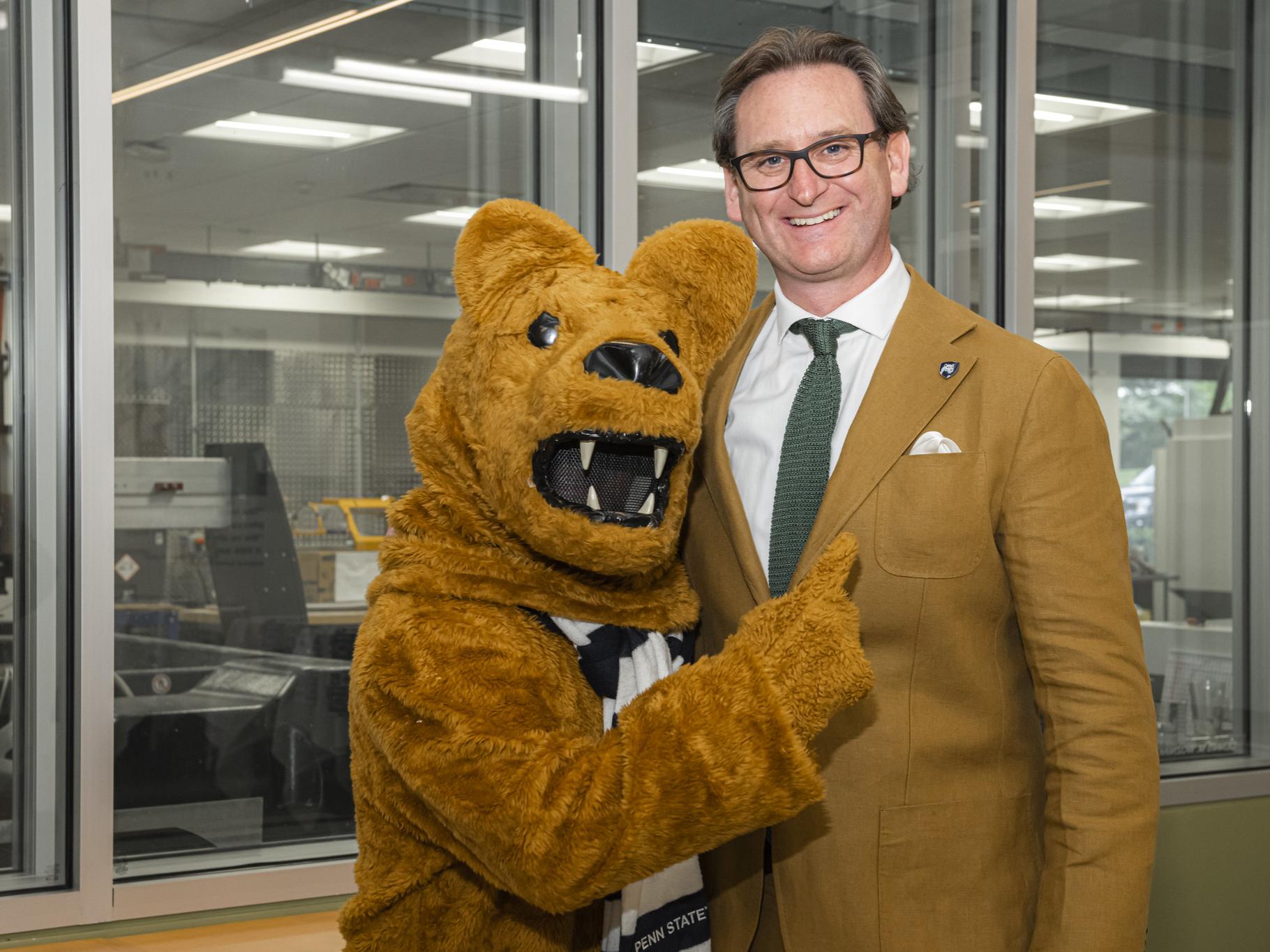 Colin J. Neill smiles and poses with the Nittany Lion