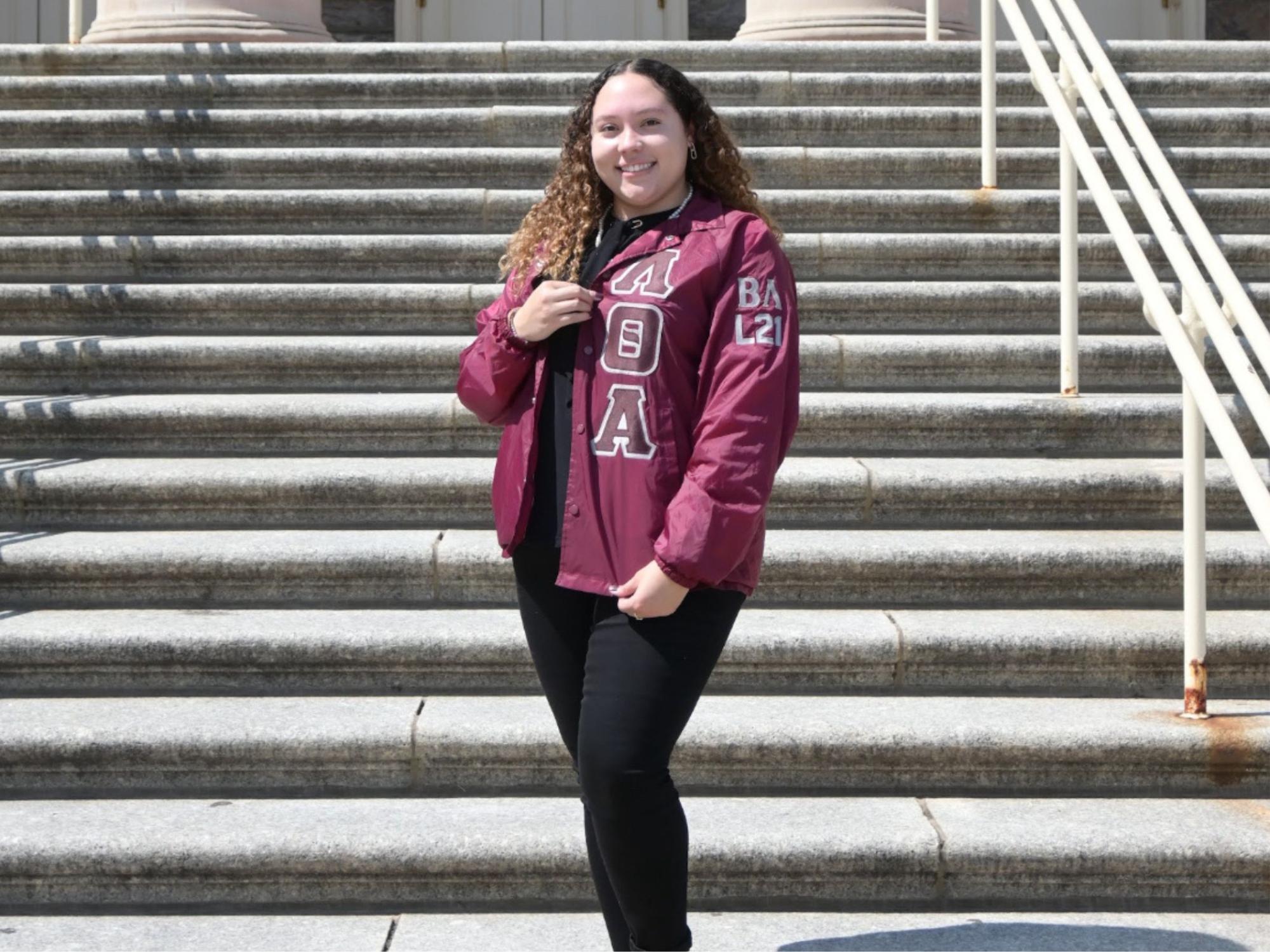 Jayden Foxx stands in front of the steps at the main entrance to Old Main.