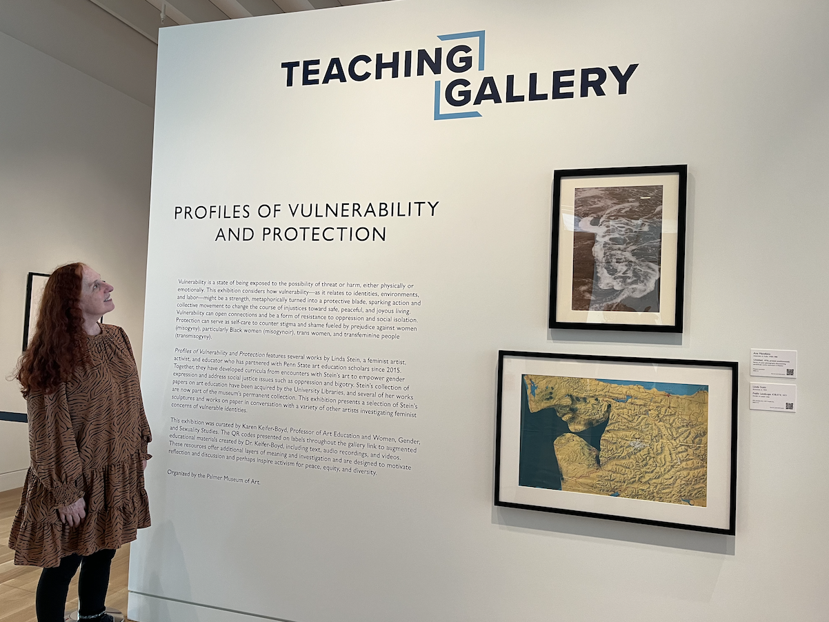 A woman standing next to a gallery wall
