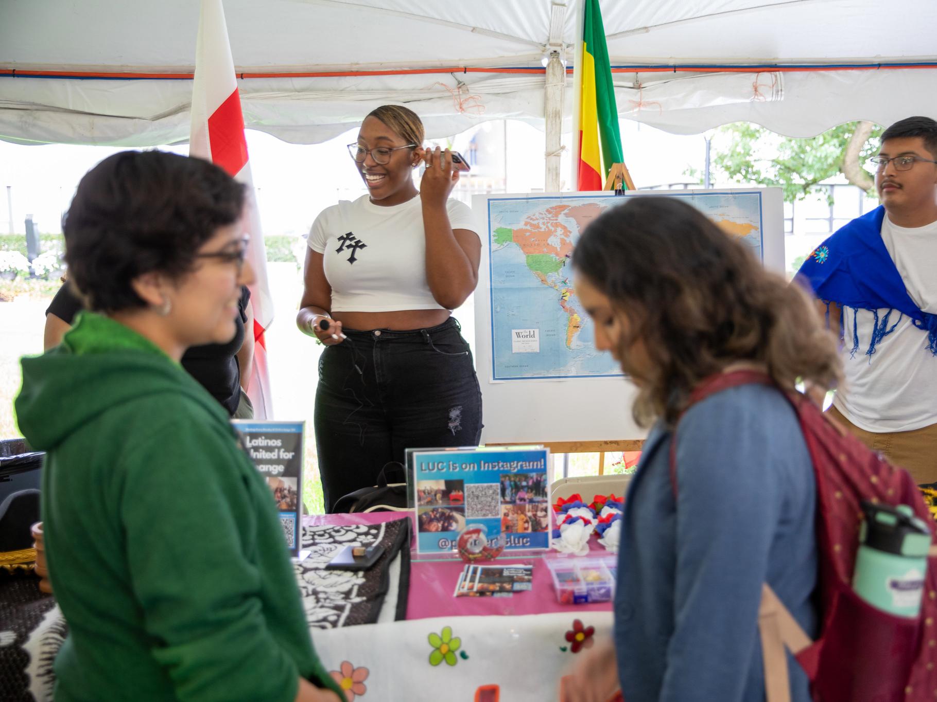 Two students learn about Latinos United for Change club while two students man the table