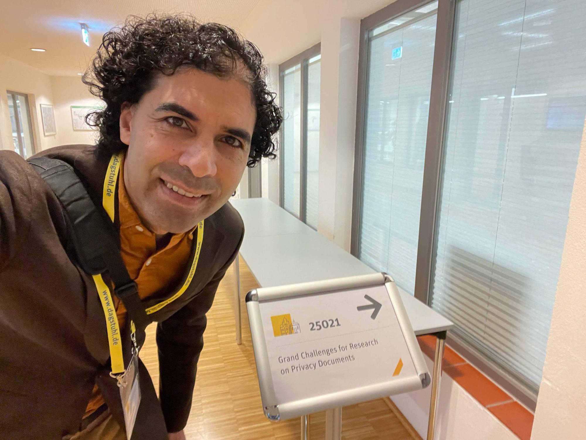 person wearing lanyard smiles at entrance to conference