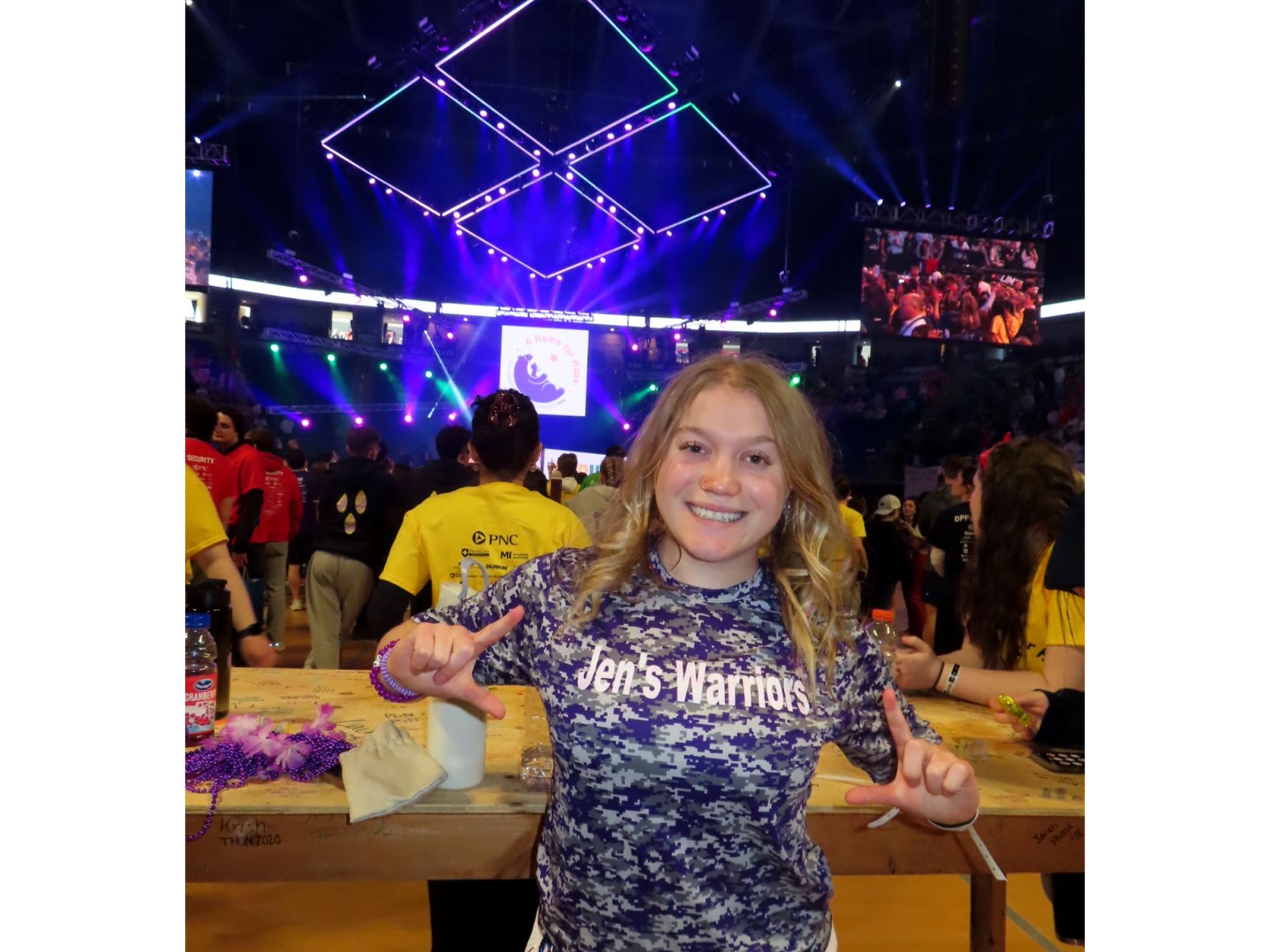 Penn State DuBois student Paige Miller stands on the dance floor of the Bryce Jordan Center during THON 2025 wearing a “Jen’s Warriors” tee shirt in remembrance of her mother, who passed away in 2019 after a battle with cancer.