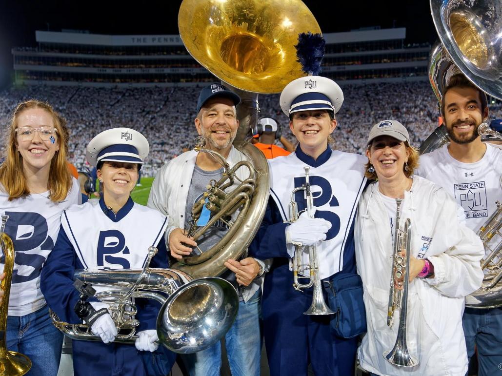 The Arnoldi family smiles for a photo while holding their instruments in Beaver Stadium.