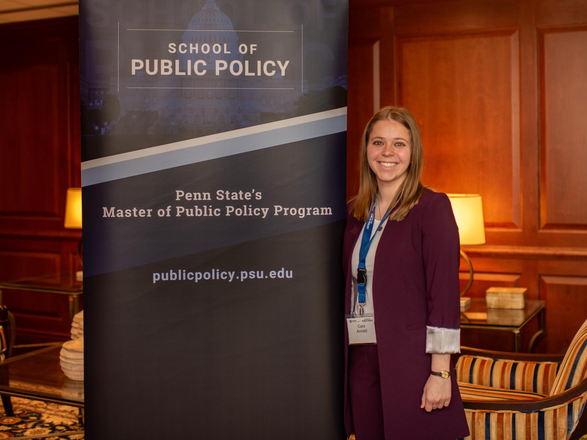 Cara Arnoldi stands with a School of Public Policy banner while on a trip to Washington, D.C.
