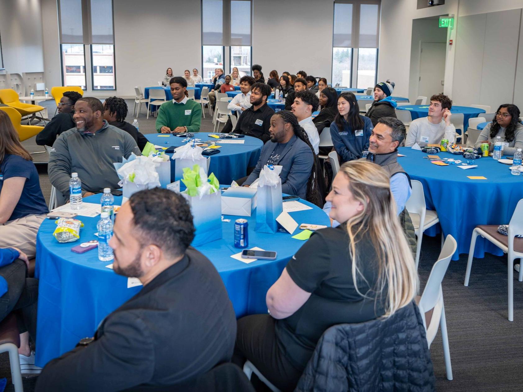 students, alumni, and industry partners sit at round tables at event