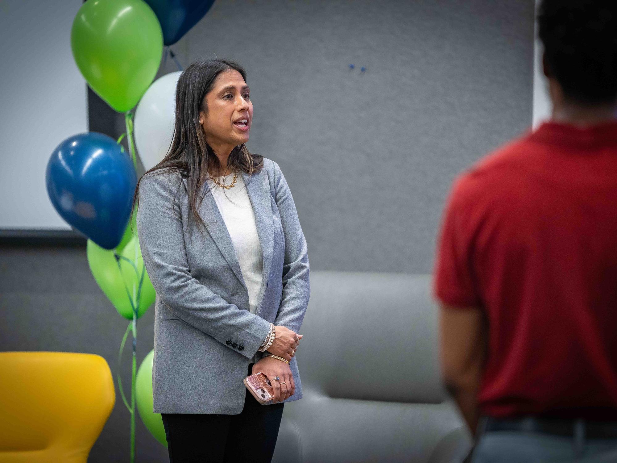 person with long dark hair and blazer speaking