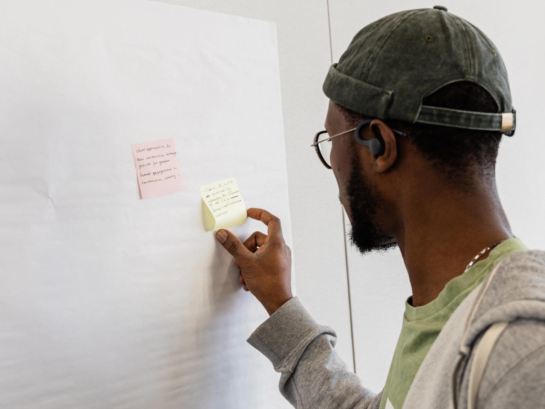 A man places a post it note on the wall