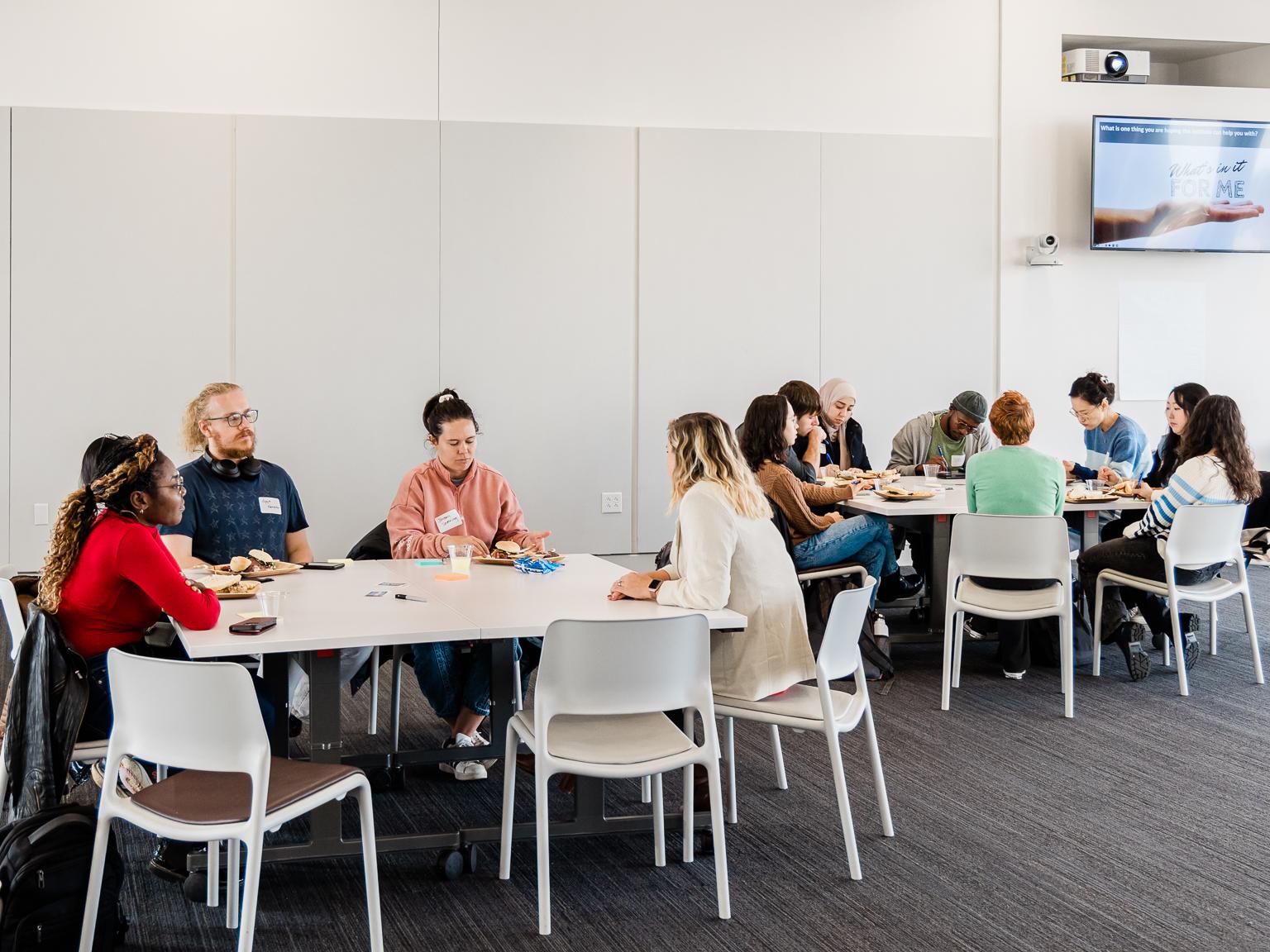Groups of people sitting at 2 conference tables.
