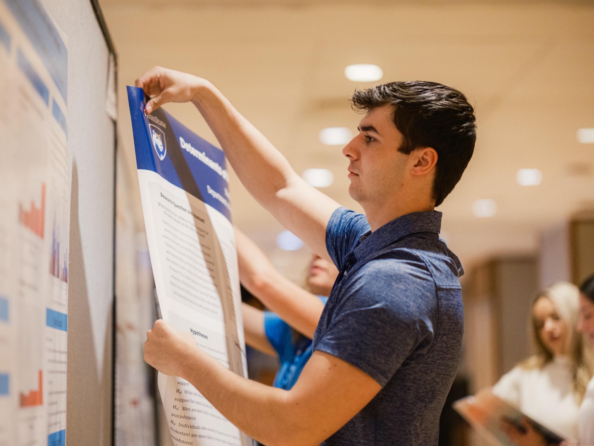 Student putting up research poster