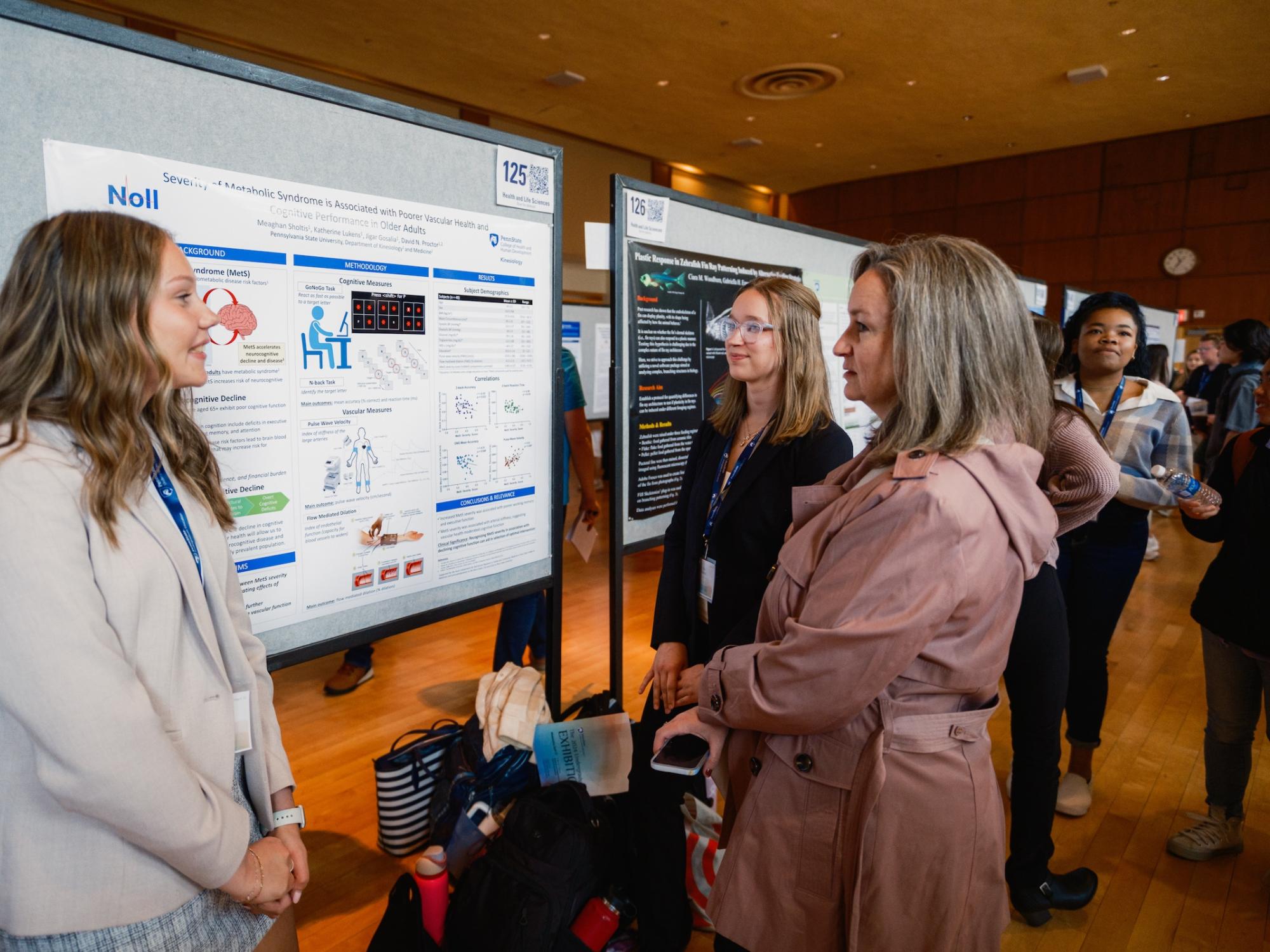Two students presenting research poster to judge