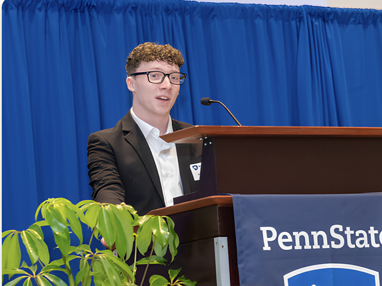 Nick Hotalen, wearing a suit, speaks at a podium during an Atherton Society Luncheon.