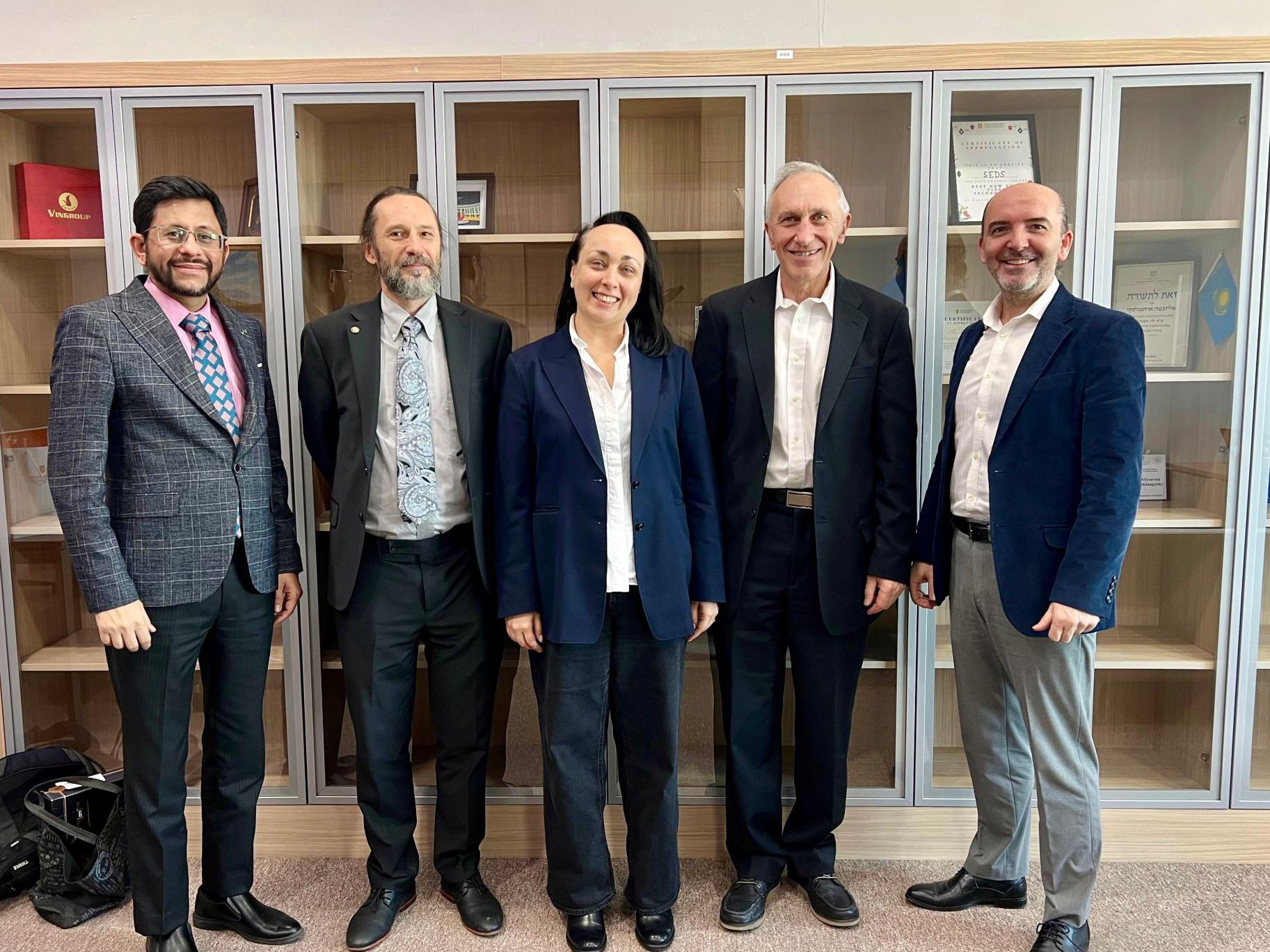 Five people smiling for the camera in a room