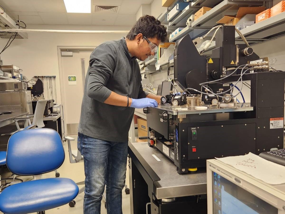 Person working in lab on electrical test machine with chair in foreground