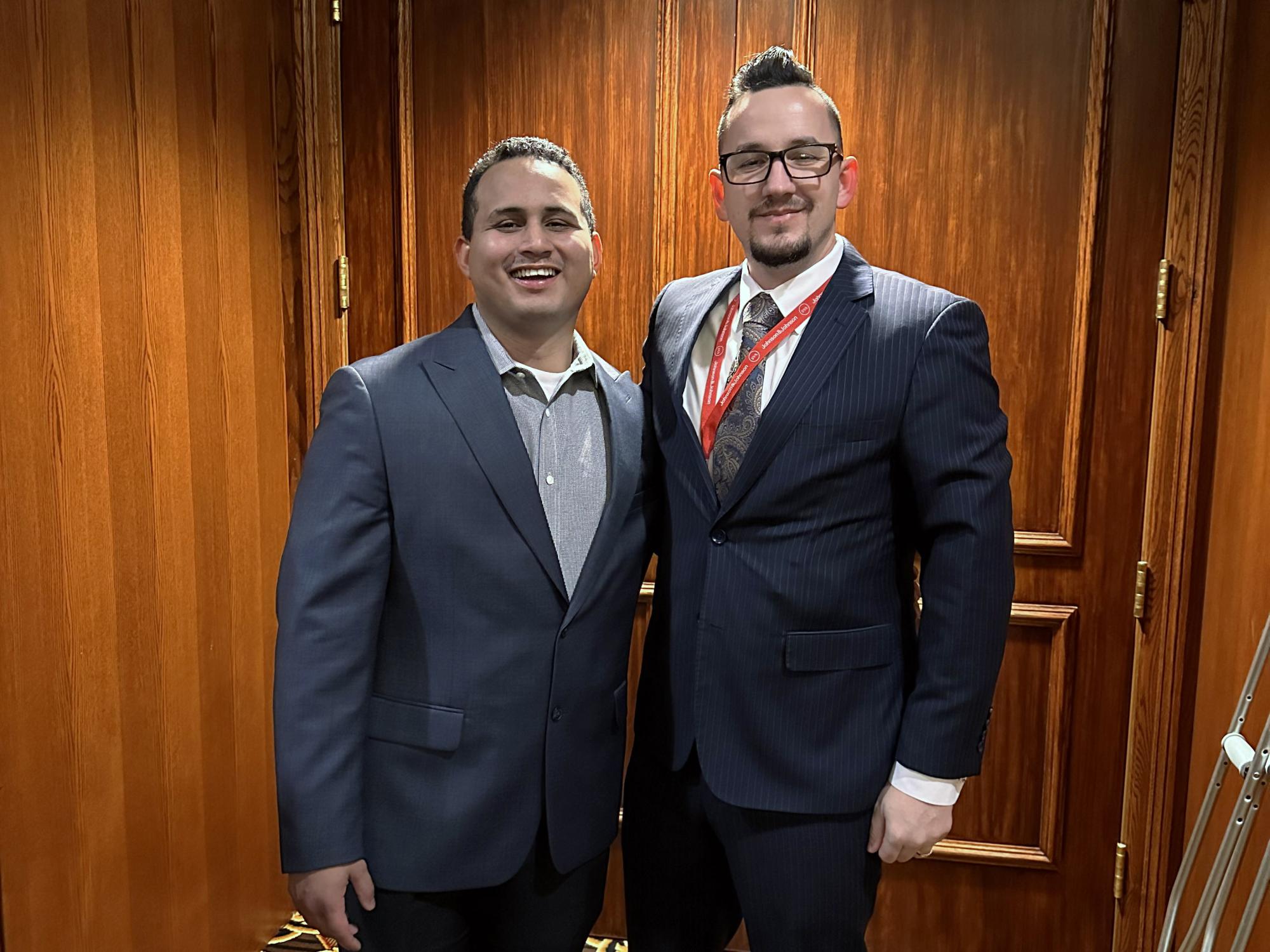 two men in suits stand next to each other