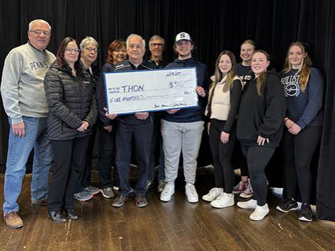 A group of people holding a large check and participating in a check presentation. 