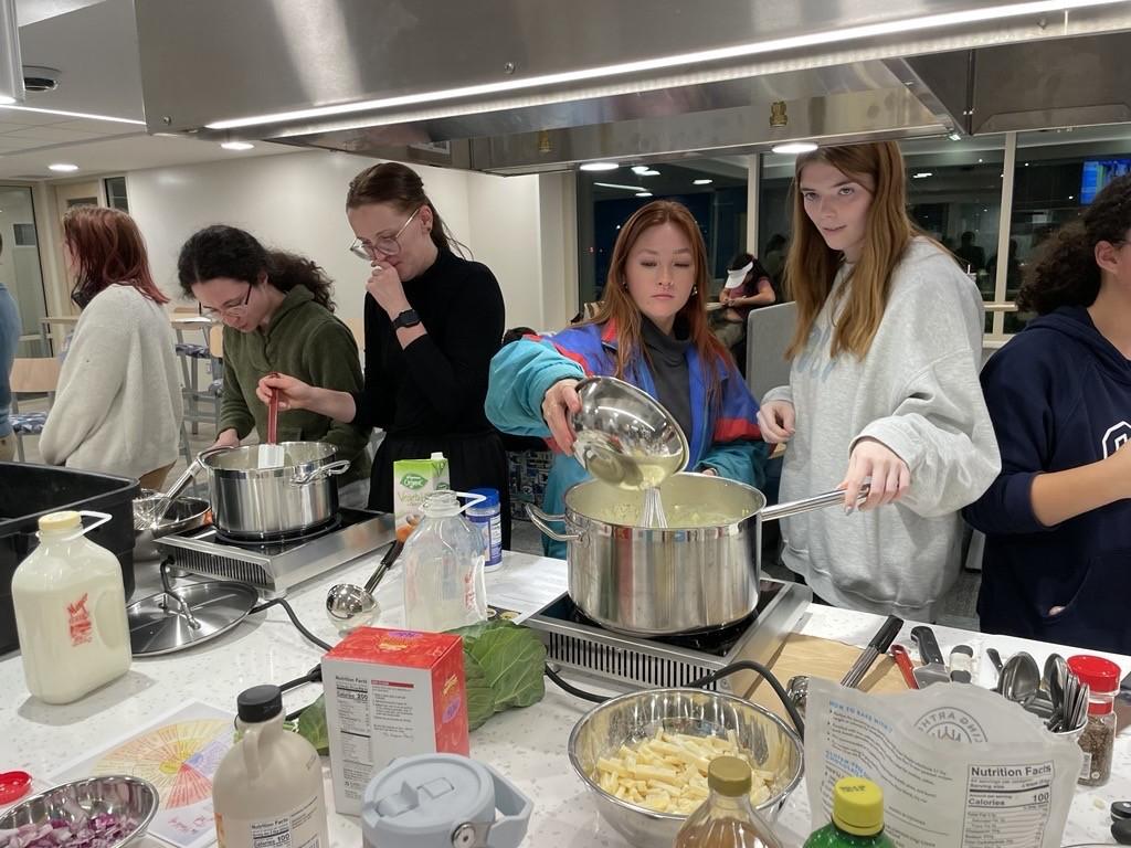 Students add ingredients to their soup pot during a cooking demonstration.