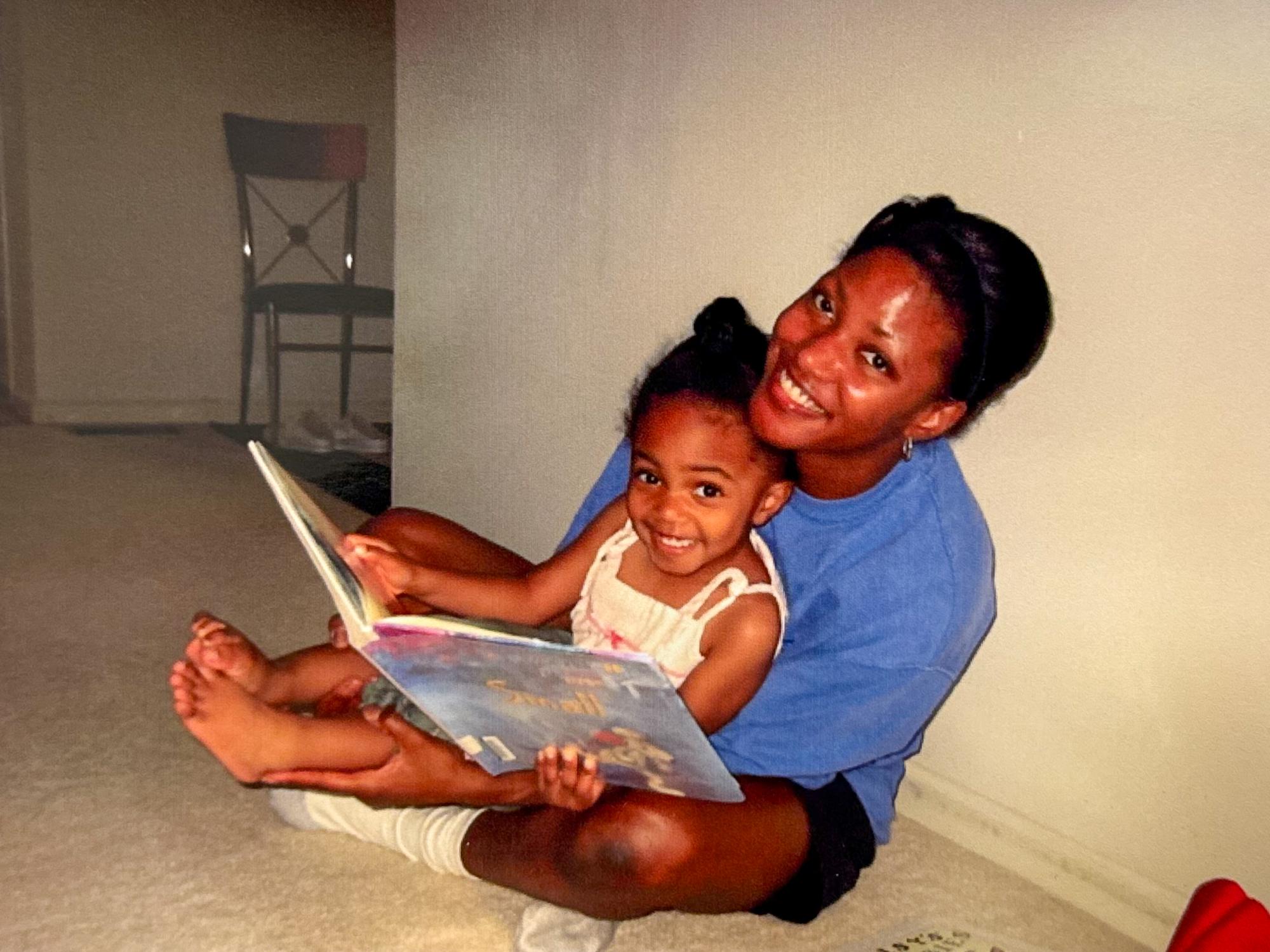 A mom and baby sit on the floor reading a library book.