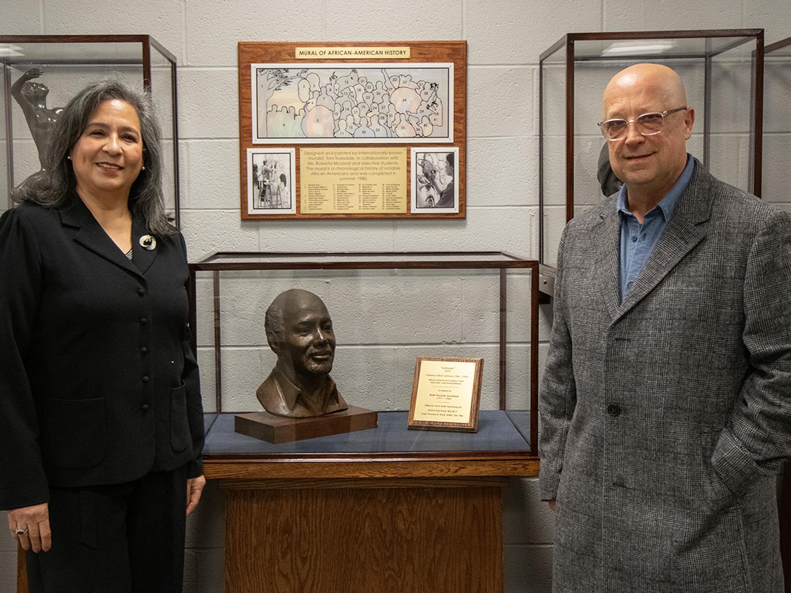 Evelyn Toro Knull and Doug Knull stand next to a sculpture of Oliver LaGrone