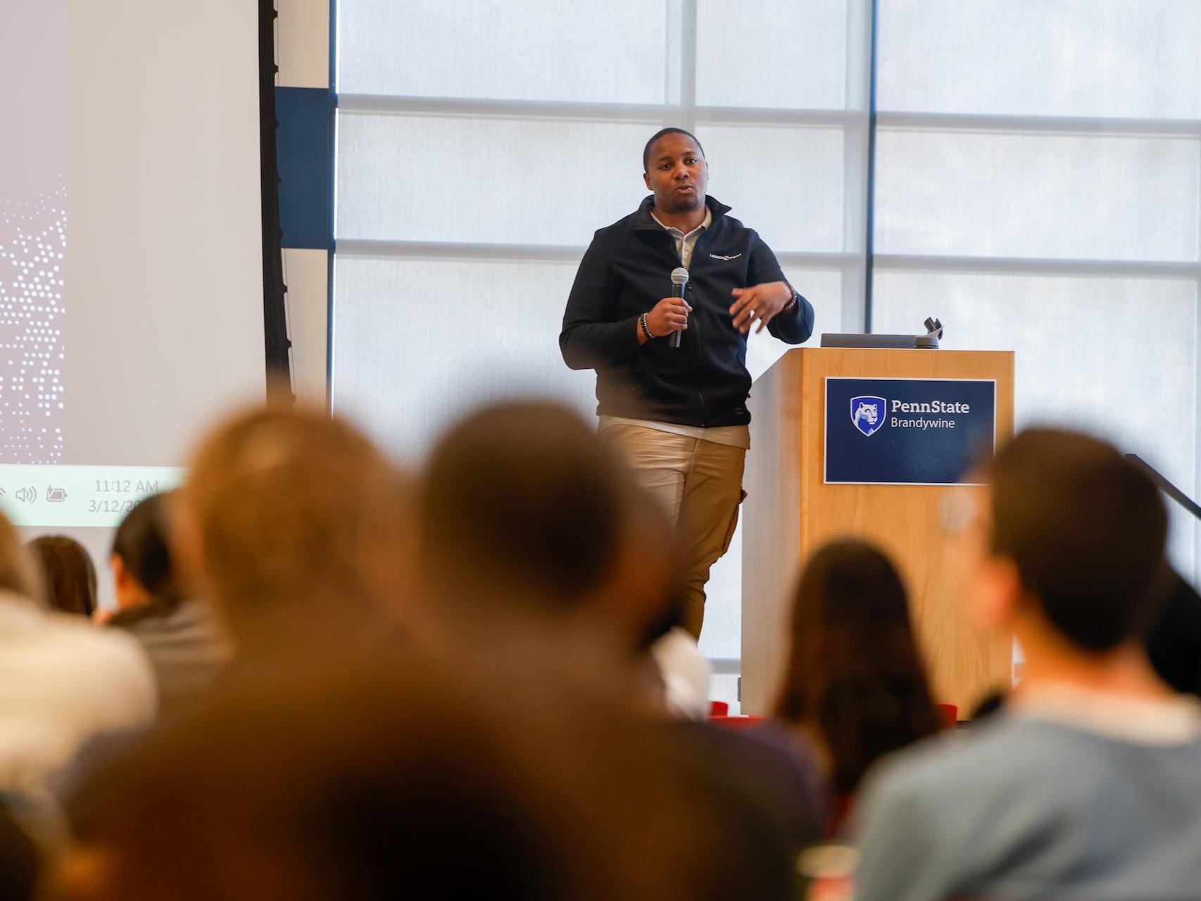 man talking in front of a crowd