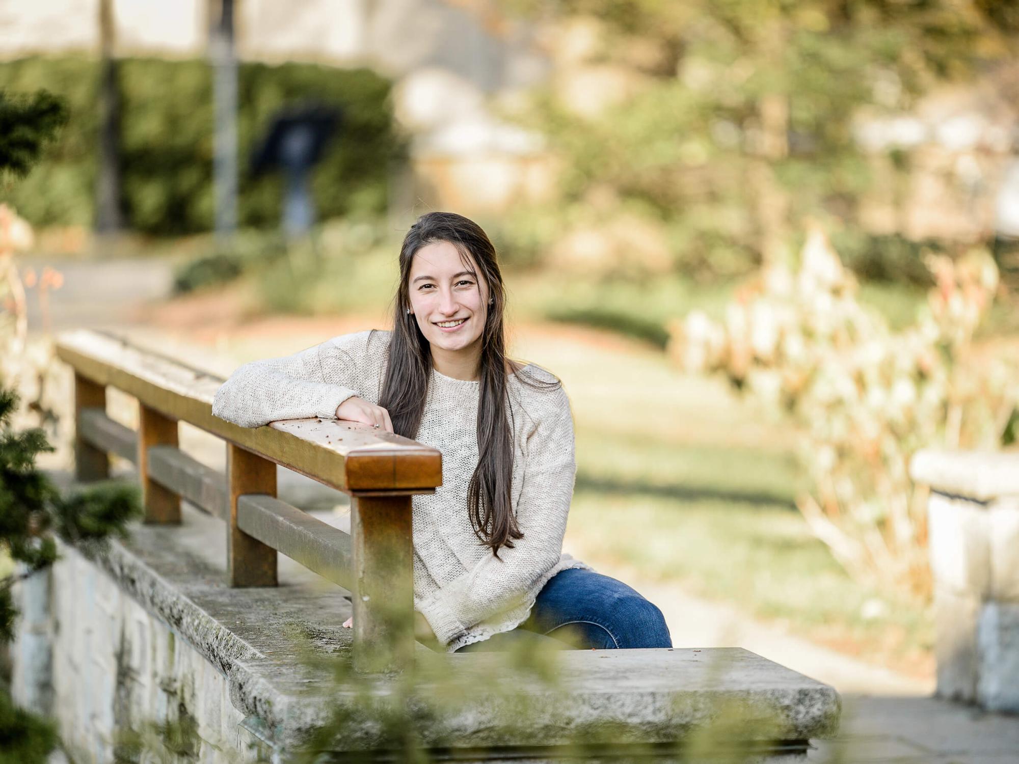 Maria Rebecca Duiker sits on a bridge outside the Hintz Family Alumni Center at Penn State University Park.